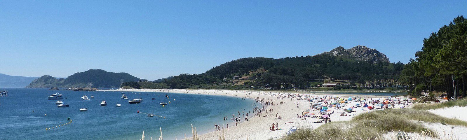 Panorámica de la playa de Rodas, en las Islas Cíes, con el agua turquesa y barcos fondeados
